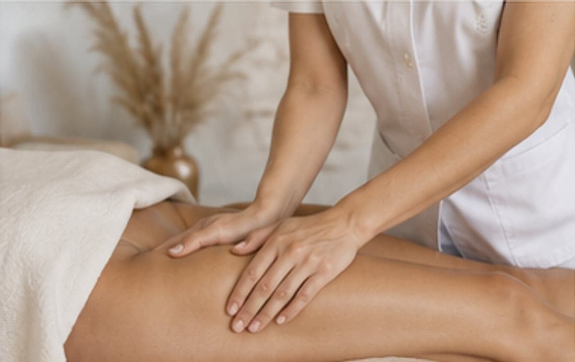 Hands performing slow lymphatic drainage strokes over a client's lower back